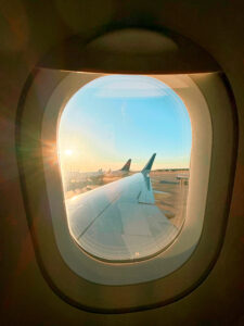 image of an airplane window looking out at a sunset on a long-haul international flight