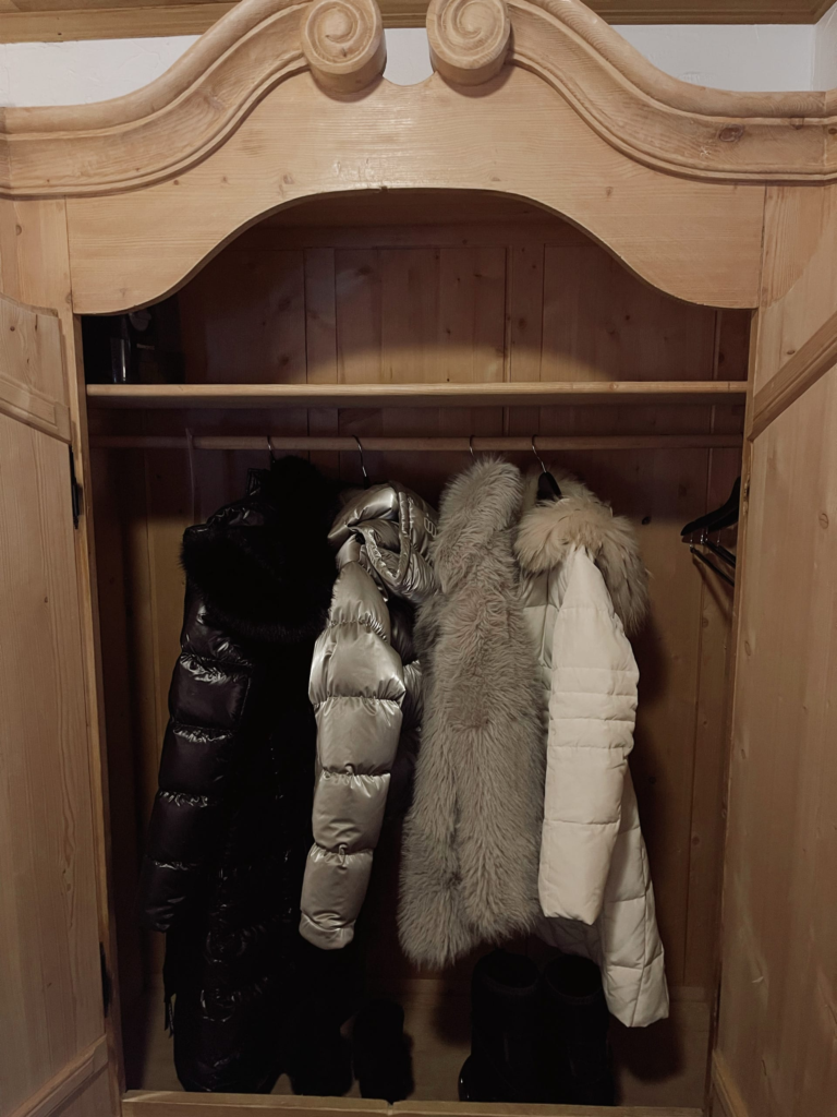 puffer jackets and fur coats aesthetically hung in a closet for après ski