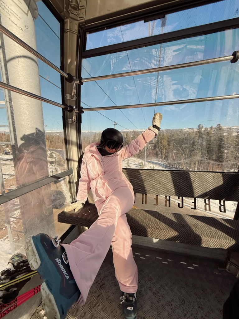 woman in gondola and pink ski outfit posing