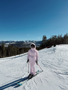 woman in a pink ski outfit skiing in Colorado
