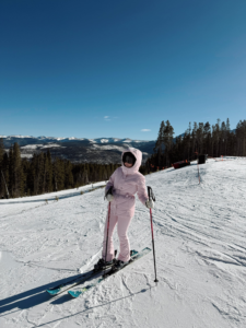 woman in a pink ski outfit skiing in Colorado